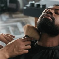 photo d’un barbier utilisant une brosse sur la barbe de son client après l’avoir coupé - hairstyle photos et images de collection