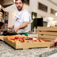 pizzaiolo at work - chef is shovelling the pizza out of the oven into the pizza box - junk food stock pictures, royalty-free photos & images