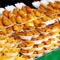 plates of fried food for sale in market - junk food stock pictures, royalty-free photos & images