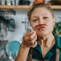 playful chef making mustache with dry chili pepper while standing in kitchen - food stock pictures, royalty-free photos & images