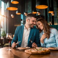 playful couple eating pizza together in a restaurant. - food stock pictures, royalty-free photos & images