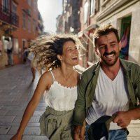 playful couple having fun while running on the street. - travel stock pictures, royalty-free photos & images