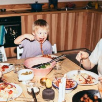 playful kids having meal with parents while sitting at dining table in home - food stock pictures, royalty-free photos & images