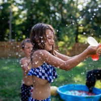 playful siblings playing with water bombs at backyard - garden decoration stock pictures, royalty-free photos & images