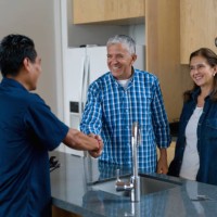 plumber greeting happy clients at home with a handshake - home decoration stockfoto's en -beelden