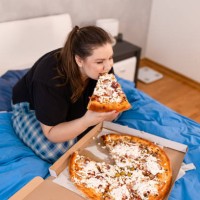 plus size woman eating pizza alone in the morning - junk food stock pictures, royalty-free photos & images