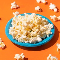 popcorn in a blue plastic plate on orange background - junk food stock pictures, royalty-free photos & images