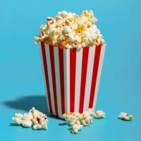 popcorn in red striped container over blue background - junk food stock pictures, royalty-free photos & images