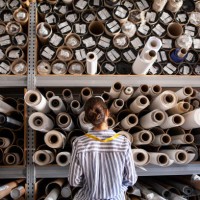 porträt des textildesigners, der stoff aus einem stapel von rollen in einer nachhaltigen werkstatt auswählt - fashion stock-fotos und bilder