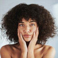 porträt, schönheit und gesicht mit einer schwarzen frau im studio, um natürliche hautpflege oder behandlung zu fördern. gesicht, haut und wellness mit einer attraktiven jungen frau, die ihre wangen berührt für die dermatologi