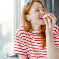 portrait of a beautiful woman enjoying eating a doughnut - food stock pictures, royalty-free photos & images