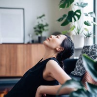 portrait of a beautiful young asian woman relaxes by the sofa in the living room, with her eyes closed and head up, enjoying the tranquility during leisure time at cozy home - home decoration stock pictures, royalty-free phot