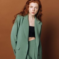 portrait of a beautiful young redhead fashion model woman looking at the camera on a color brown background.lady posing in the studio in a green suit. the concept of sale of clothes and fashion. - fashion stock pictures, roya