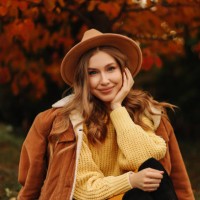 portrait of a beautiful young woman in a stylish hat and warm clothes smiling and walking in nature in an autumn park in autumn. a fashionable girl in a sweater and jacket relaxes and rests alone among the trees in cold weath