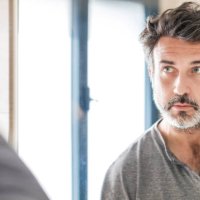 portrait of a handsome bearded 50 years old man looking at his white hair in the bathroom mirror at home. self care concept. - hairstyle photos et images de collection