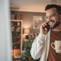 portrait of a handsome caucasian man standing by the window with a cup of coffee in his home - coffee stockfoto's en -beelden