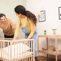 portrait of a happy couple preparing a crib for their soon to come baby - home decoration stock pictures, royalty-free photos & images
