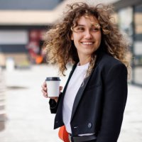 portrait of a happy, stylish young businesswoman commuting to work with a cup of coffee in her hand - junk food stock pictures, royalty-free photos & images