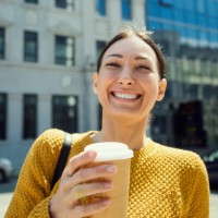 portrait of a happy young brunette woman with takeout coffee in urban background ,looking at camera - junk food stock pictures, royalty-free photos & images