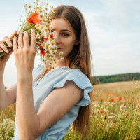 portrait of a malty beautiful woman in a field of flowers with a bouquet of daisies and poppies. the girl looks at the camera and smiles - fashion stock pictures, royalty-free photos & images