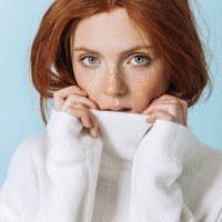 portrait of a red-haired woman in a white sweater with freckles looking into the camera close-up. - fashion stock pictures, royalty-free photos & images