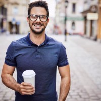 portrait of a smiling man with glasses holding coffee outdoors - junk food stock pictures, royalty-free photos & images