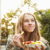 portrait of a teenage girl eating french fries - food stockfoto's en -beelden