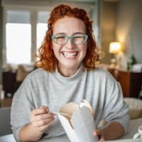 portrait of a woman taking a lunch break while working from home - junk food stock pictures, royalty-free photos & images