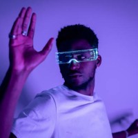 portrait of a young african american man in futuristic fashion illuminated glasses with purple neon light. concept of the future, modern technologies, technological progress, cyclops glasses - fashion stock pictures, royalty-