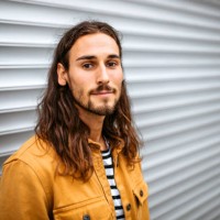 portrait of a young handsome man with long hair standing on a street, looking at camera. - fashion stock pictures, royalty-free photos & images