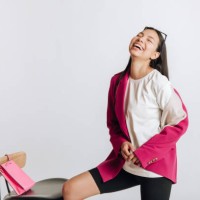 portrait of a young laughing asian woman in a jacket in a studio on a white background - fashion stock pictures, royalty-free photos & images