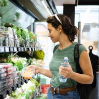 portrait of a young woman buying fresh vegetables at the grocery store - food stock pictures, royalty-free photos & images