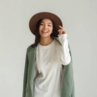 portrait of an asian smiling young woman posing in a hat and beautiful clothes on a white background in the studio. - fashion stock pictures, royalty-free photos & images