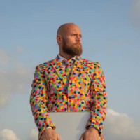 portrait of bald man with beard wearing suit with colourful polka-dots holding laptop - fashion stock-fotos und bilder