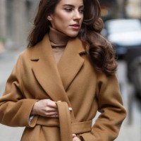portrait of beautiful lady in light brown coat tying her belt. - fashion stock pictures, royalty-free photos & images