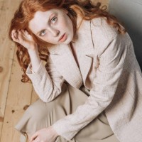 portrait of beautiful redhead woman sitting on chair looking at camera indoors. - fashion stock pictures, royalty-free photos & images