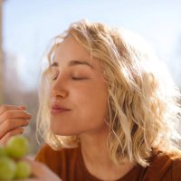 portrait of blond young woman eating green grapes - food stock pictures, royalty-free photos & images