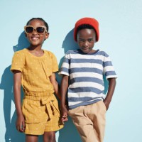 portrait of boy & girl holding hands and looking in camera, on blue backdrop in summer - fashion photos et images de collection