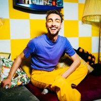 portrait of cheerful young man sitting on sofa in living room - fashion stock pictures, royalty-free photos & images