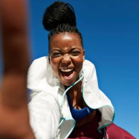 portrait of cheerful young sportswoman with hair bun against clear blue sky - hairstyle stock pictures, royalty-free photos & images