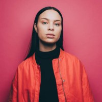 portrait of confident woman wearing orange jacket over pink background - fashion stock-fotos und bilder
