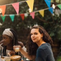 portrait of confident young woman holding drink while sitting at table during garden party - garden decoration stock pictures, royalty-free photos & images