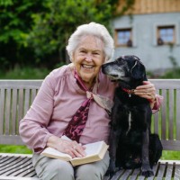 portrait of elderly woman sitting on bench, embracing older dog. companion animals for seniors. - garden decoration photos et images de collection