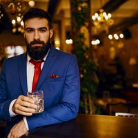 portrait of elegant young man in a bar holding tumbler - fashion stock pictures, royalty-free photos & images