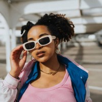 portrait of fashionable curly hair woman holding sunglasses at parking lot in sunlight - fashion stock pictures, royalty-free photos & images
