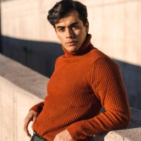 portrait of fashionable young man wearing turtleneck pullover leaning on a wall at sunlight - fashion stock pictures, royalty-free photos & images