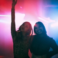 portrait of happy young female friends standing with arms around at nightclub - concert stock pictures, royalty-free photos & images