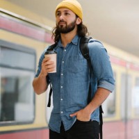 portrait of man with backpack and coffee to go waiting at platform, berlin, germany - junk food stock pictures, royalty-free photos & images