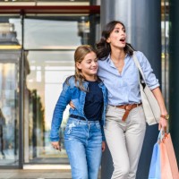 portrait of mother and daughter standing near the shopping window and browsing the store. - fashion stock pictures, royalty-free photos & images