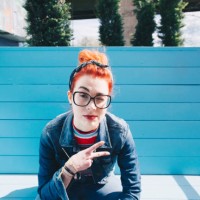 portrait of redhead young woman gesturing peace sign while sitting on bench - fashion stock pictures, royalty-free photos & images